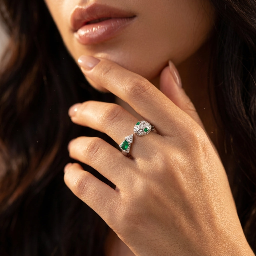 Close-up lifestyle view of a moody model showcasing a luxury emerald serpent totem open ring resting against her chin.
