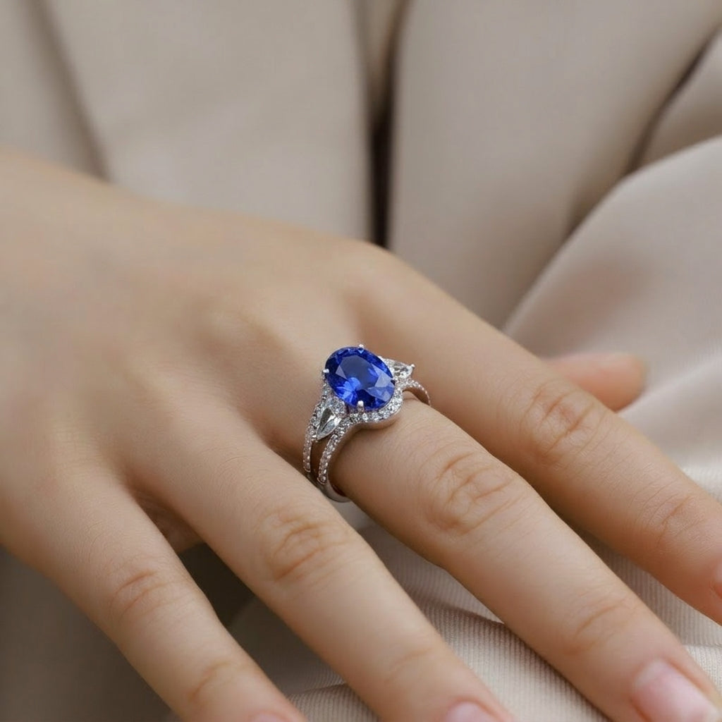 Side angle lifestyle shot of a model showcasing a luxury oval blue sapphire split-shank ring on her finger.