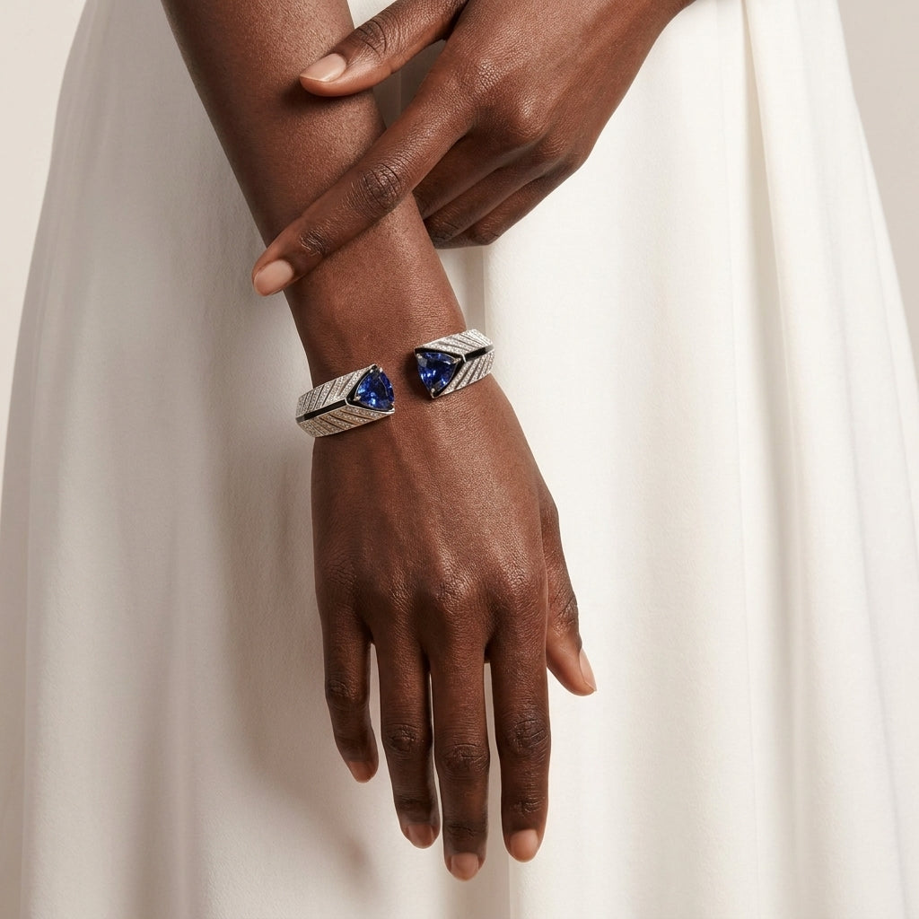 Hand wearing a silver bracelet with blue gemstones against a neutral background
