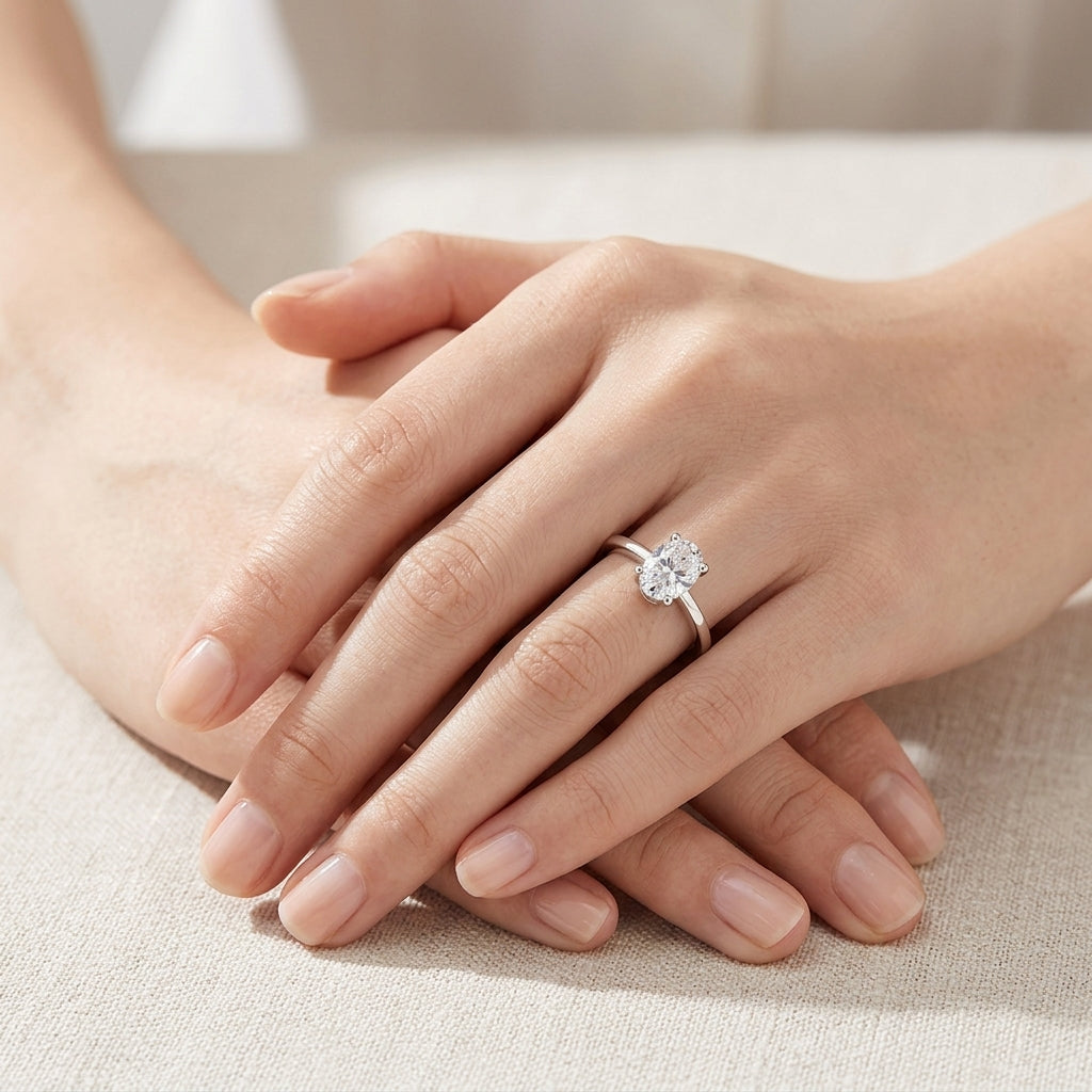 Model showing oval cut moissanite solitaire ring on hand in soft natural lighting.