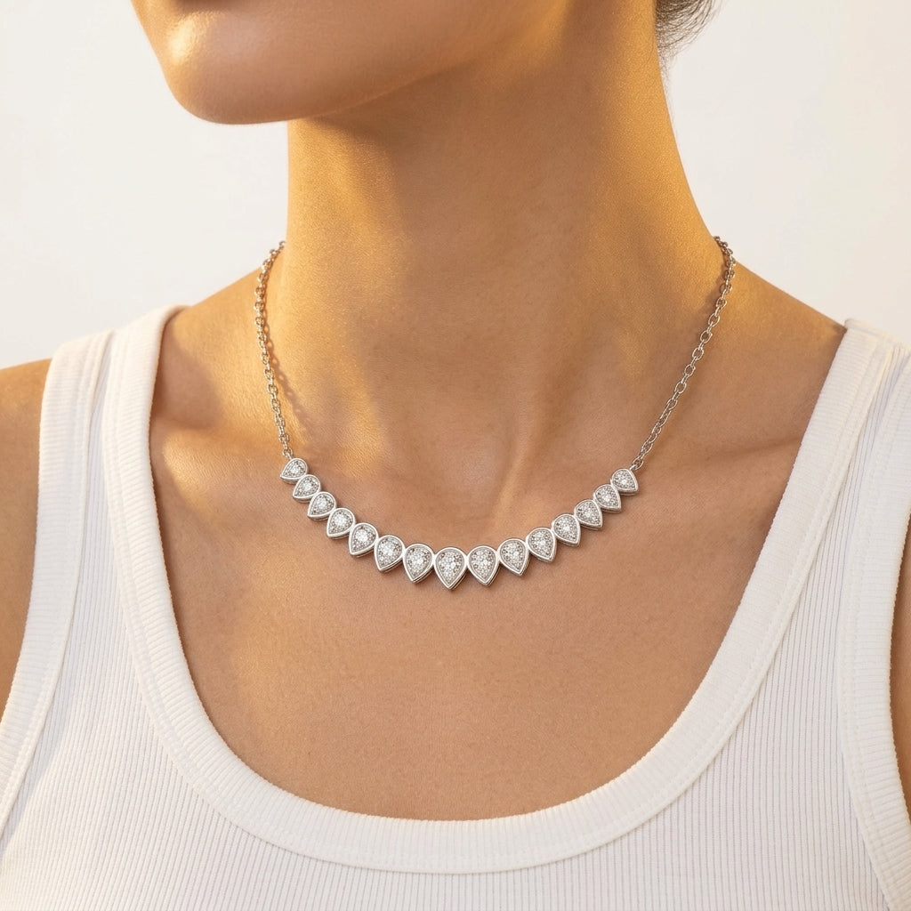 Model showing graduated pear cut moissanite curved smile necklace on collarbone.