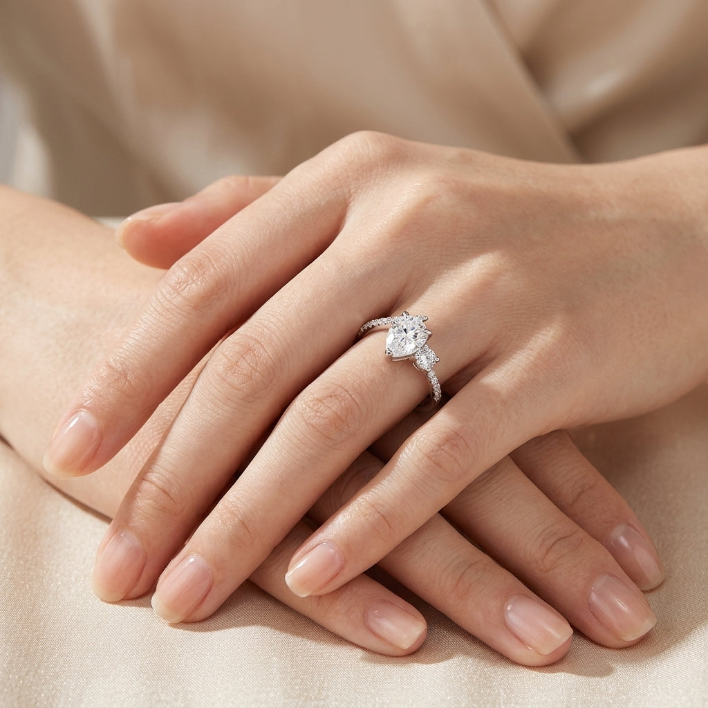 Model showing pear cut moissanite toi et moi ring on hand in warm ambient lighting.