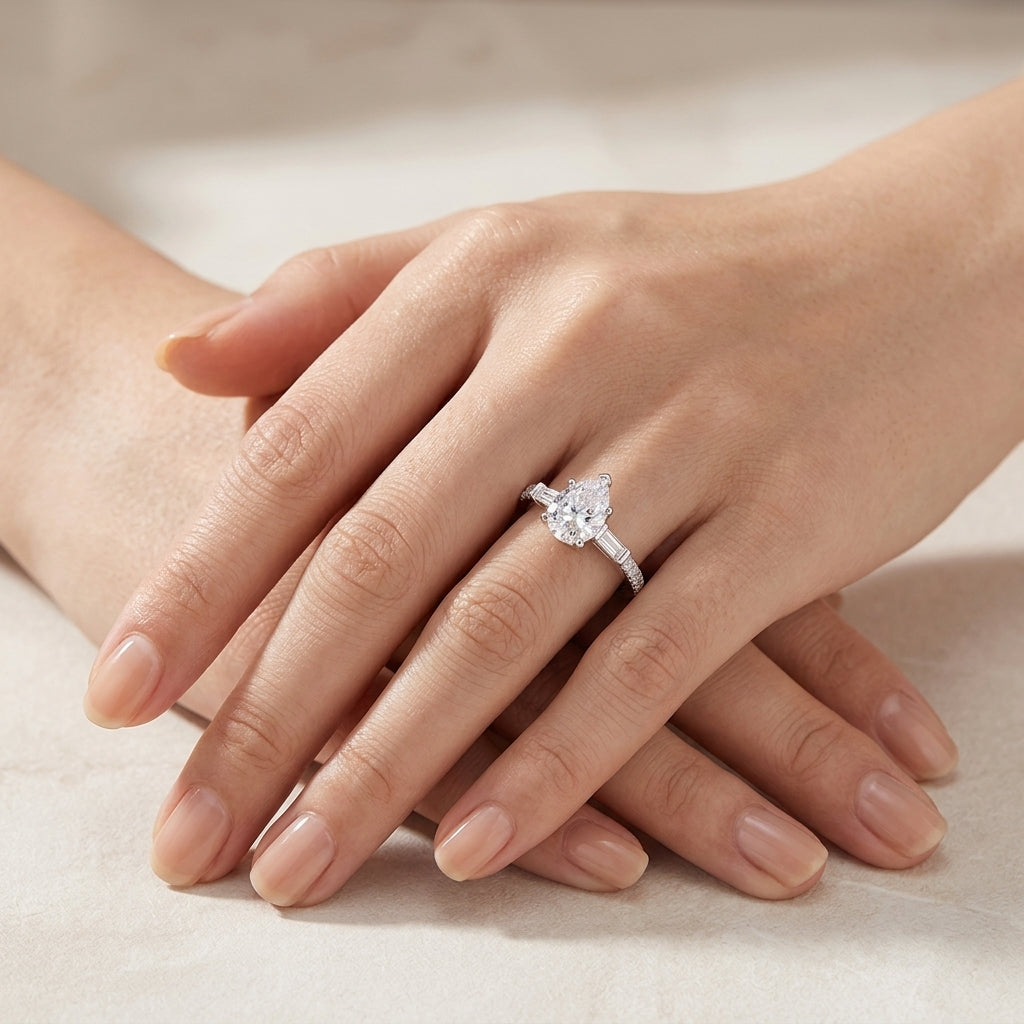 Model wearing pear cut moissanite engagement ring with baguette accent pave band in soft natural light.