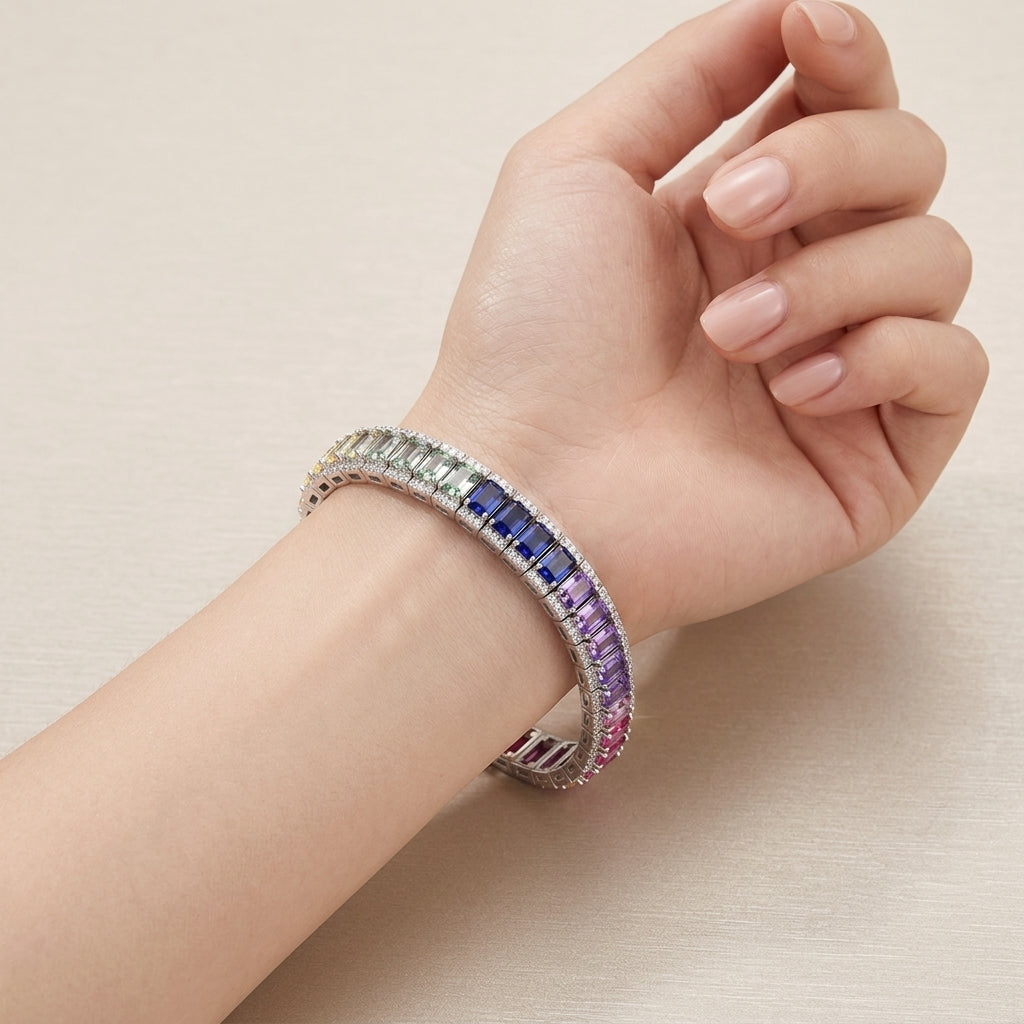 Close-up shot of model wrist showing rainbow emerald cut gemstone tennis bracelet.