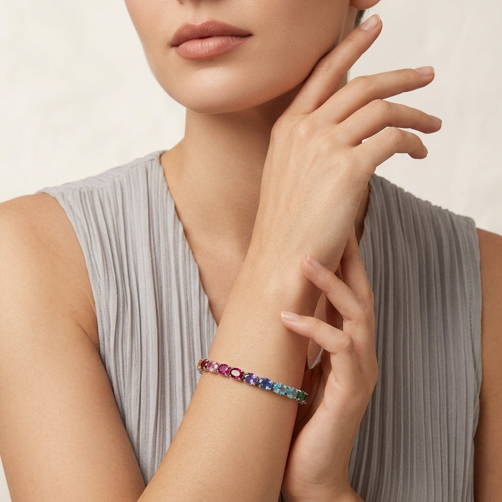 Model posing with rainbow oval cut multi-color gemstone tennis bracelet on arm.