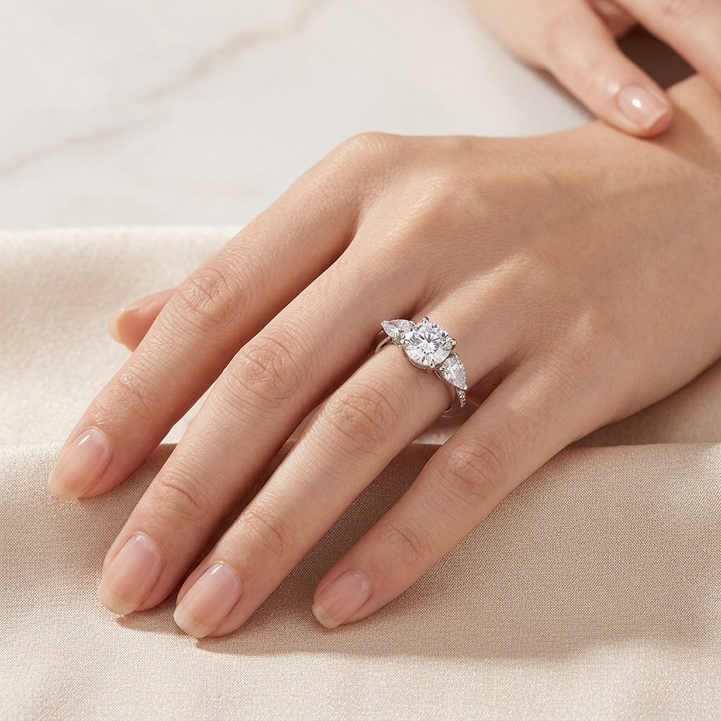 Model showing round cut moissanite three stone engagement ring on hand in soft light.