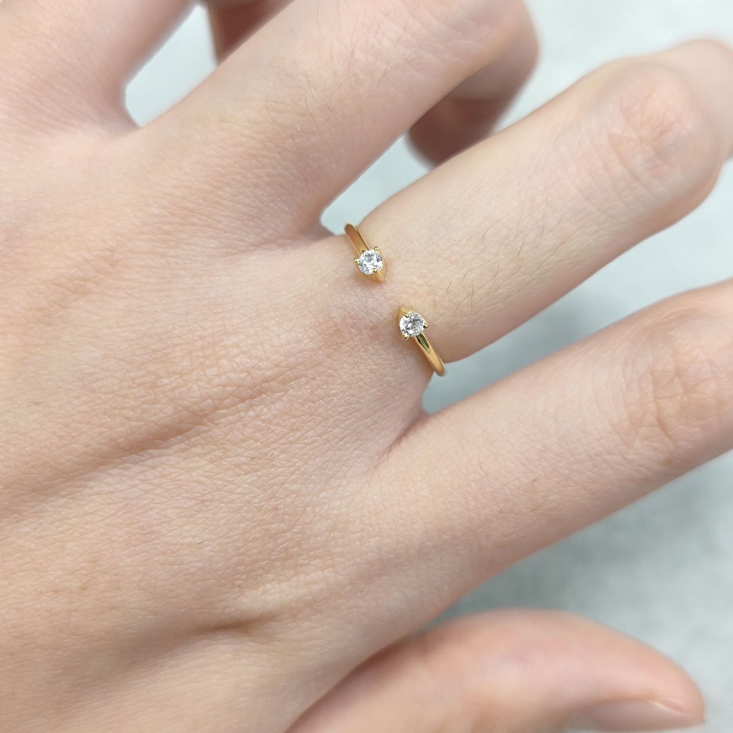 Gold rings with diamonds on a hand against a light background