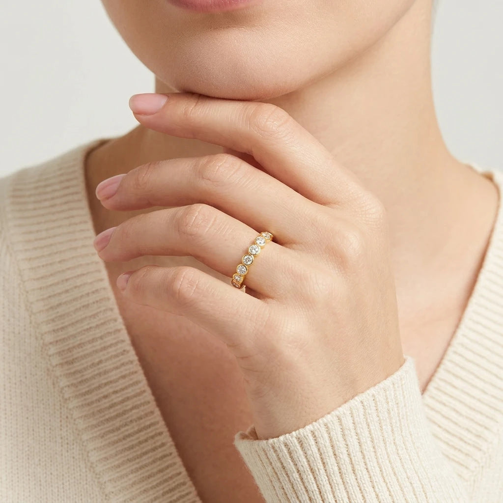 High-end fashion lookbook view of a model wearing a timeless romantic gold bezel moissanite anniversary jewelry piece with a cozy knit sweater.