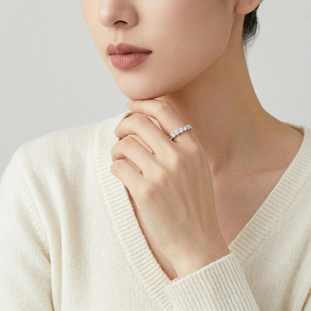 Editorial fashion lookbook portrait of a model styling a 925 sterling silver moissanite bubble half eternity ring near her neck.