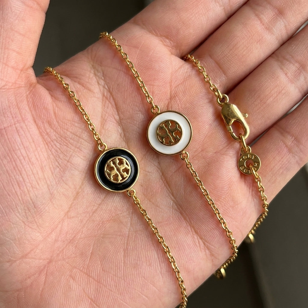 Hand-held size reference of Tory Burch Double T Necklace showing the 10mm pendant and adjustable chain length
