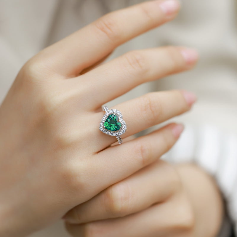 High-angle perspective view of a vintage heart-cut emerald cocktail cluster ring on a woman's hand.