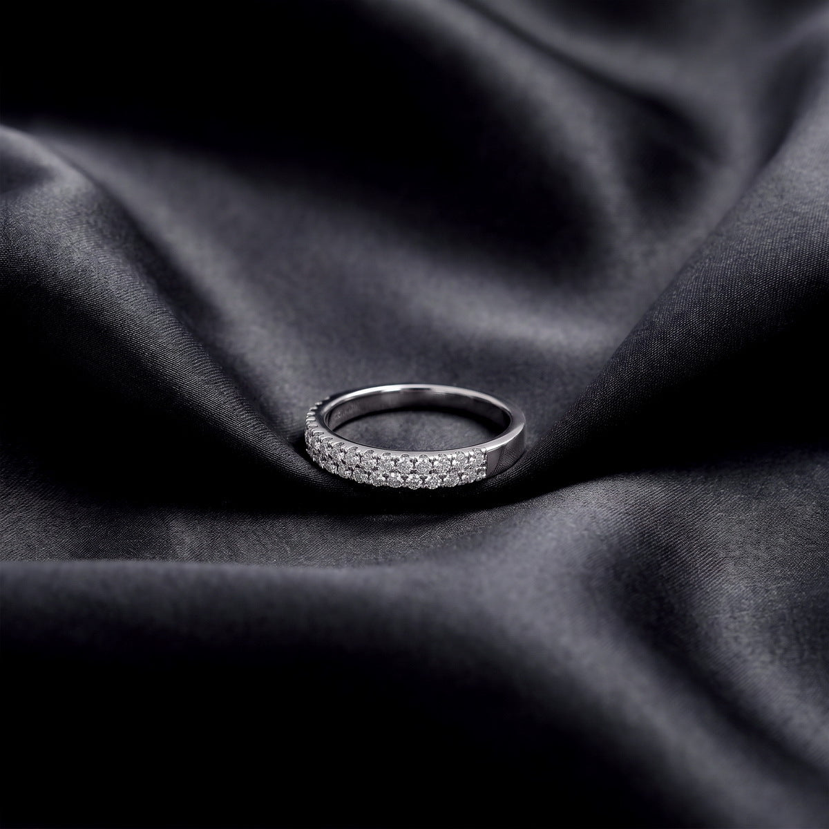 Angled view of 0.49 ctw double row pave lab grown diamond eternity ring resting on dark black silk