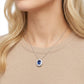 Elegant model wearing a 0.8ct oval blue sapphire pendant necklace with halo design.