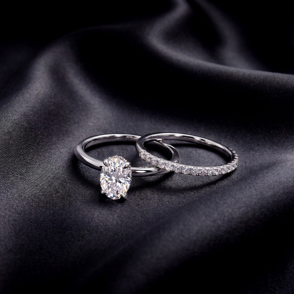 Perspective shot of 1.26ct oval solitaire ring and micro-pavé band resting separately on dark silk.