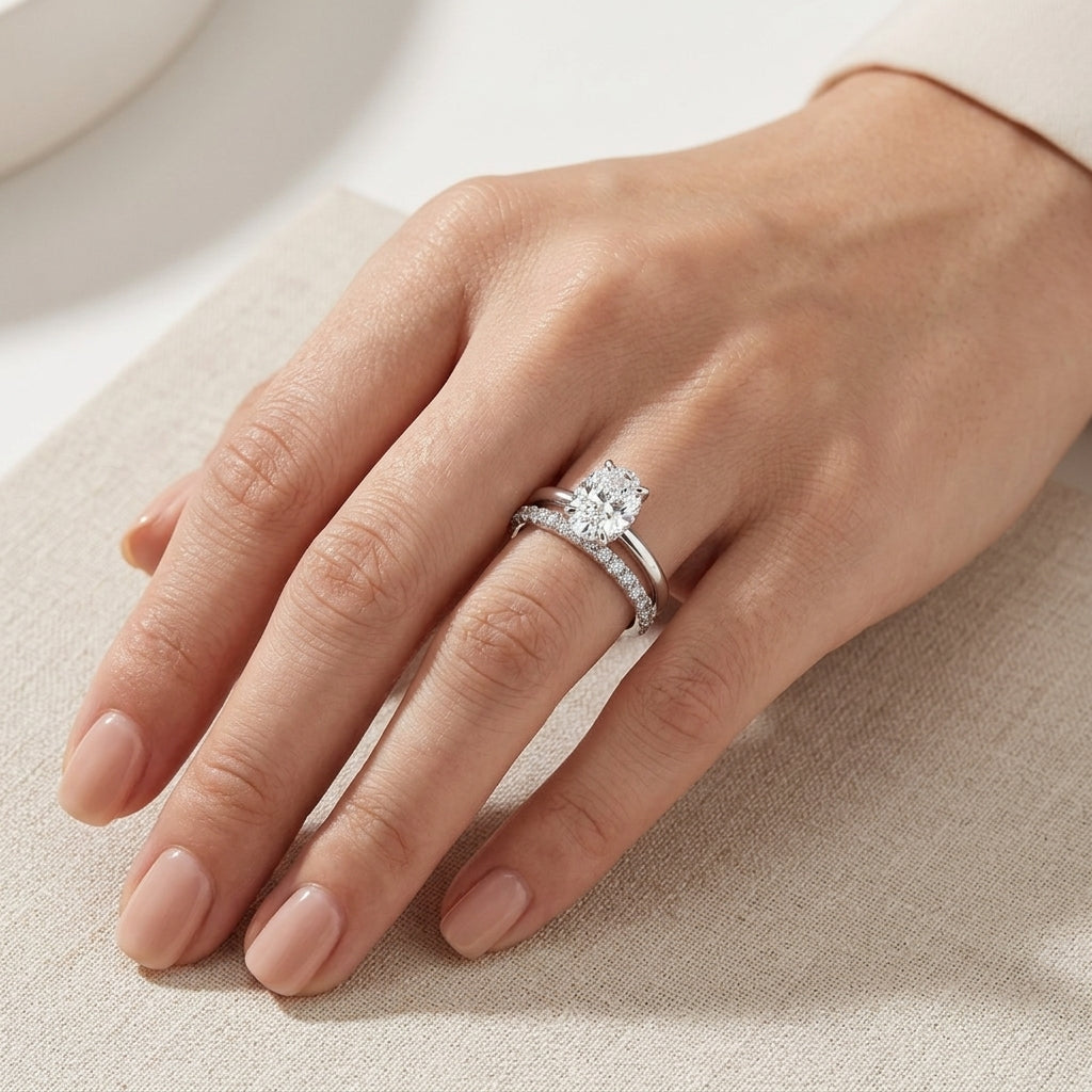 Model wearing modern 1.26ct oval cut lab diamond stacking bridal wedding ring set on ring finger.