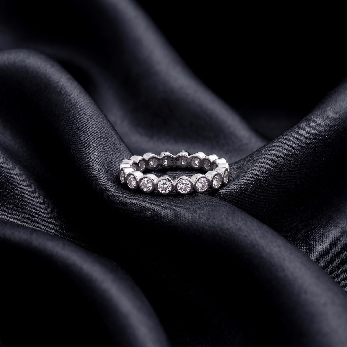 1.31 ctw bezel set round lab grown diamond eternity wedding band resting flat on dark black silk