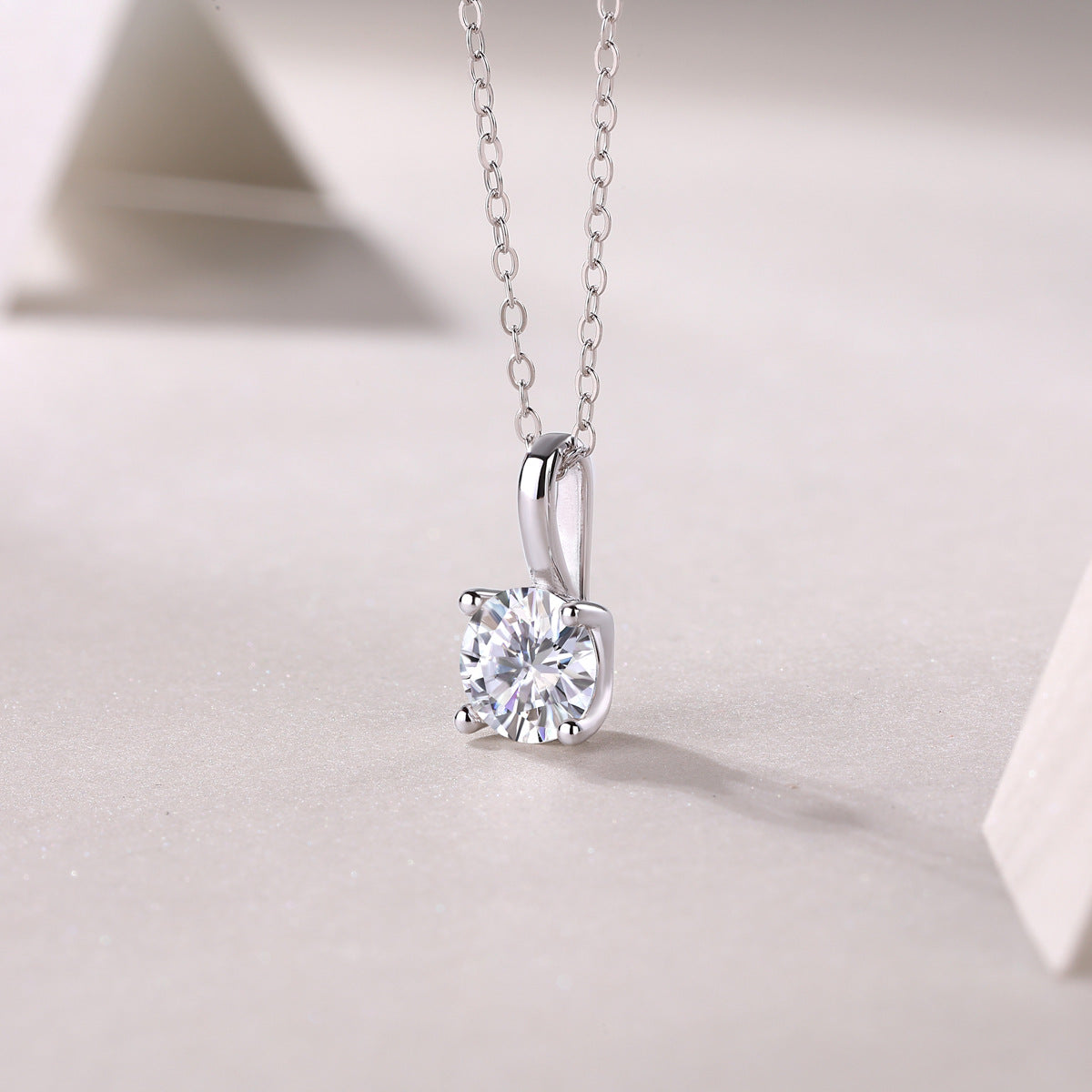 1 Carat round lab grown diamond solitaire pendant necklace resting on textured surface.