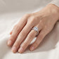 Model showing 1 carat round cut moissanite halo ring on hand in soft natural lighting.