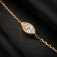 A gold chain bracelet featuring a marquise-cut diamond pendant, displayed on a textured black surface.