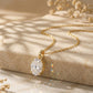 10k yellow gold 7x9mm oval cut lab diamond four-prong pendant necklace displayed on stone surface with light shadows