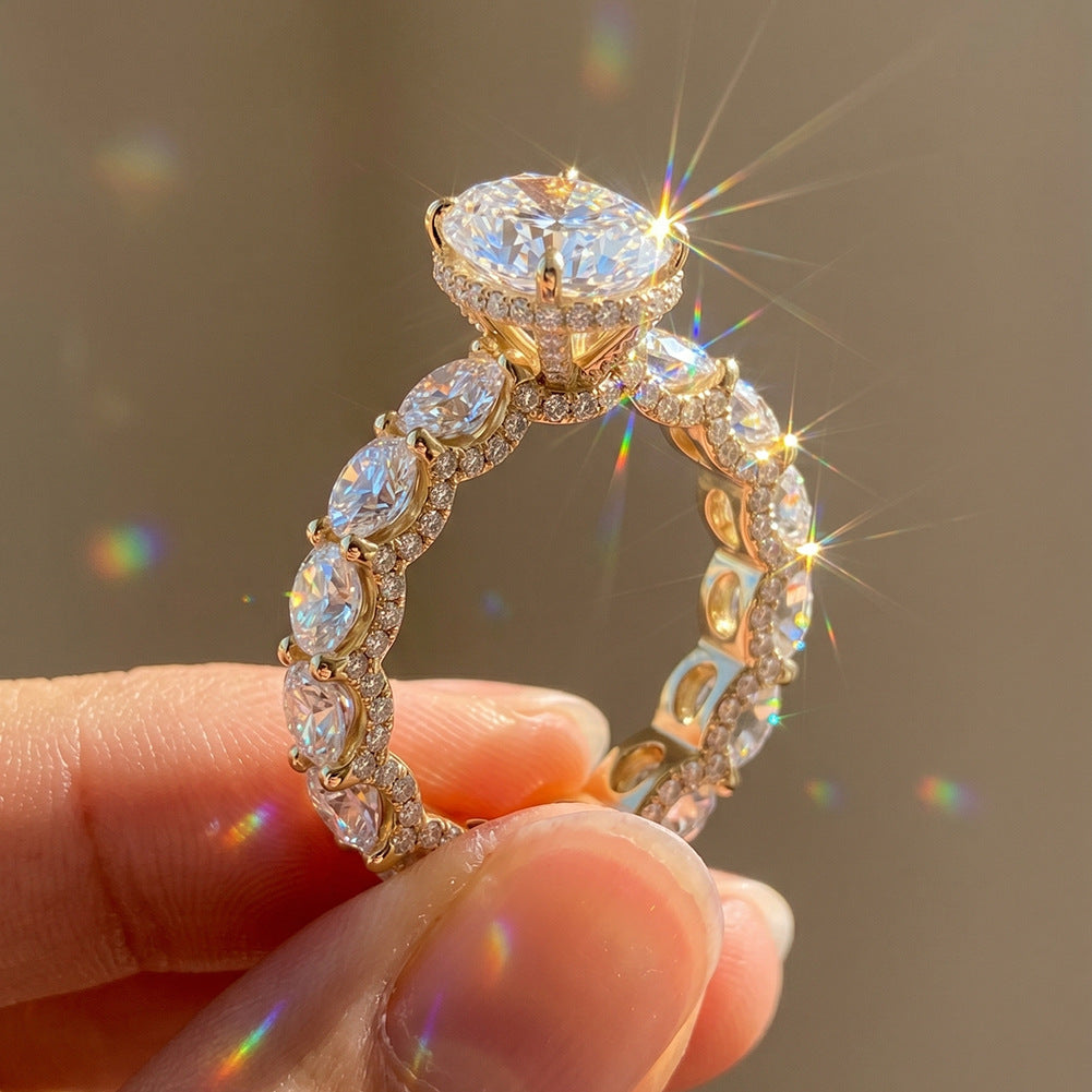 Close-up of 10k yellow gold oval cut lab diamond pave engagement ring in sunlight showing sparkle and eternity band