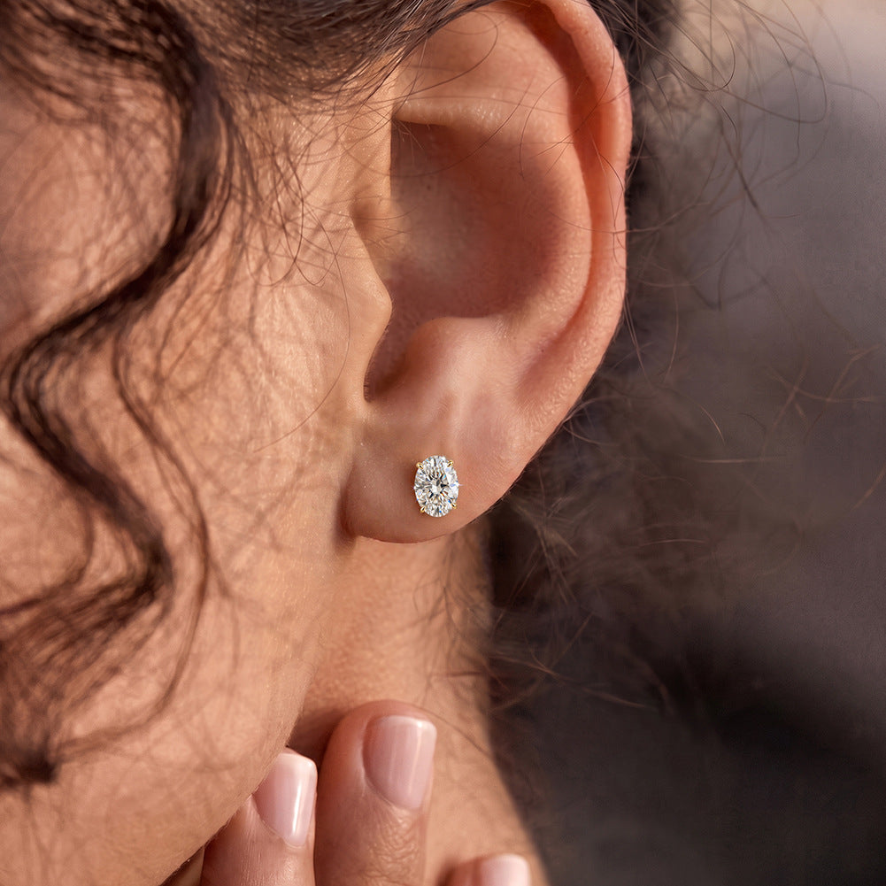 Model wearing 10k yellow gold 4x6mm oval cut lab-grown diamond stud engagement earrings on ear lobe