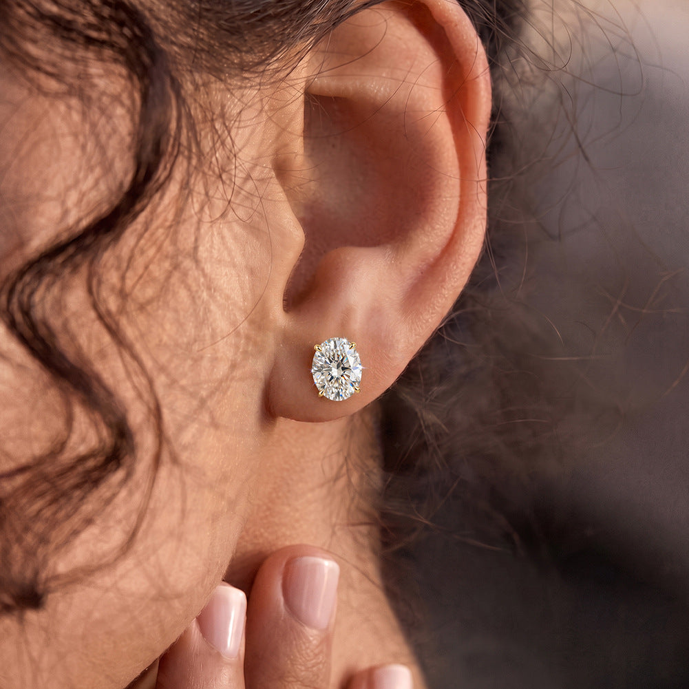 Model wearing 10k yellow gold 7x11mm oval cut lab-grown diamond stud engagement earrings on ear lobe
