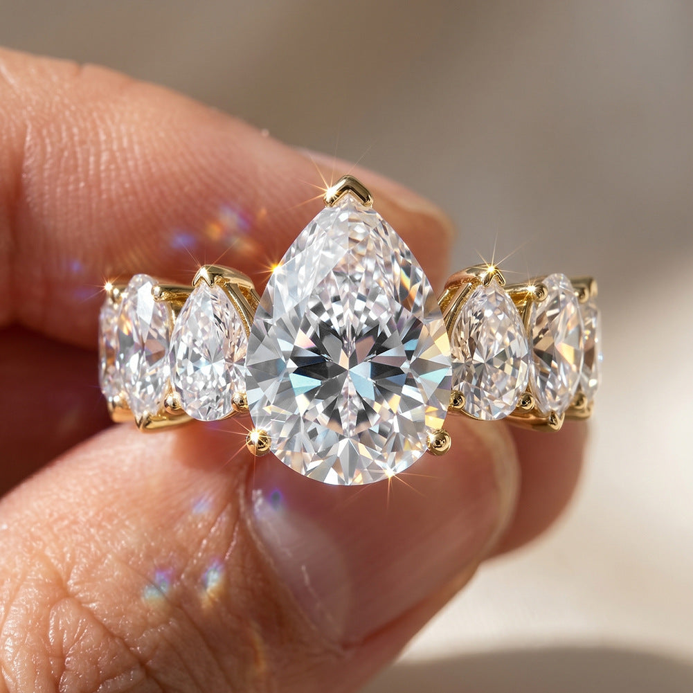Close-up of hand holding 10k yellow gold pear cut lab diamond five-stone engagement ring showing sparkle   