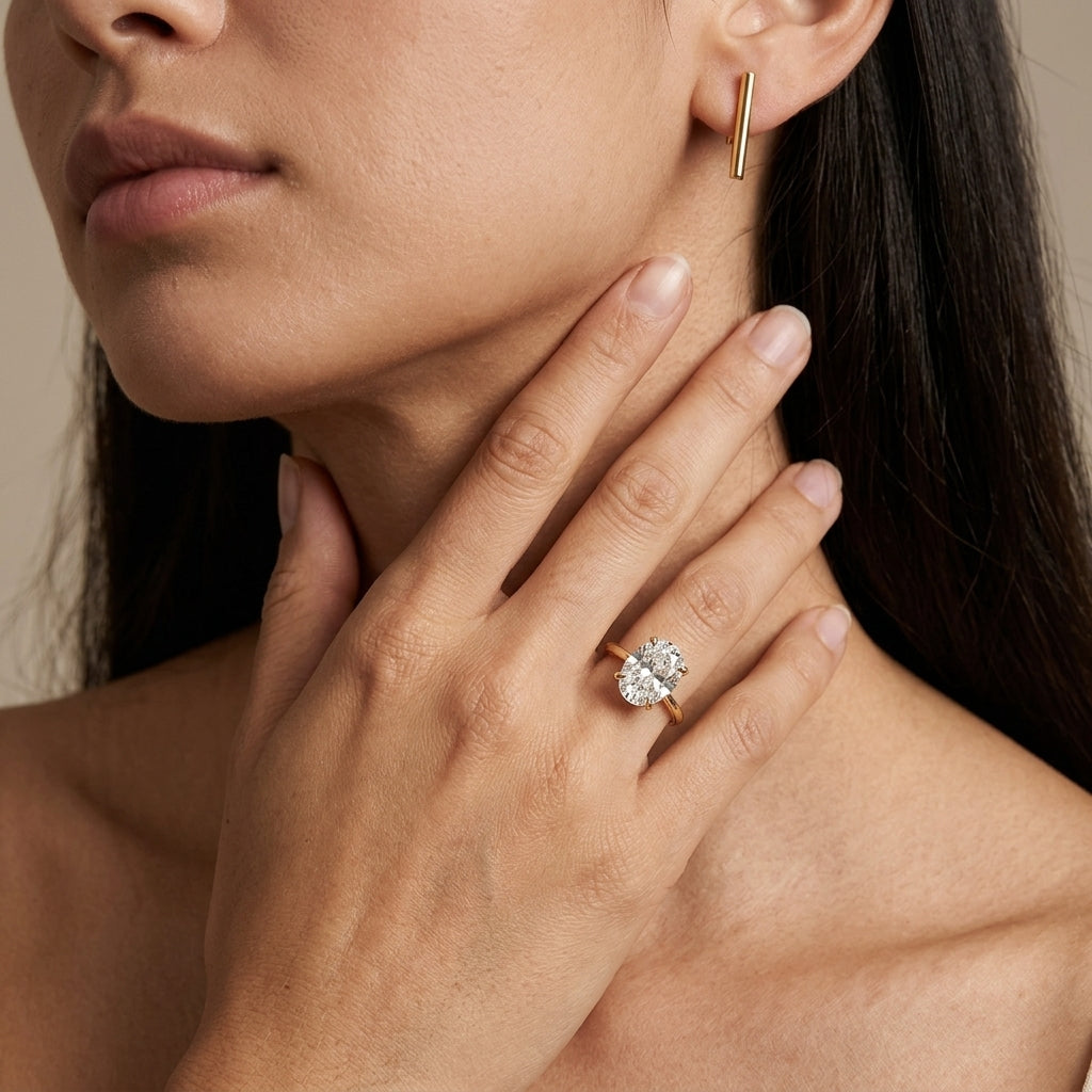 Model wearing 14k gold 2 ct oval cut lab diamond solitaire engagement ring with hand touching neck