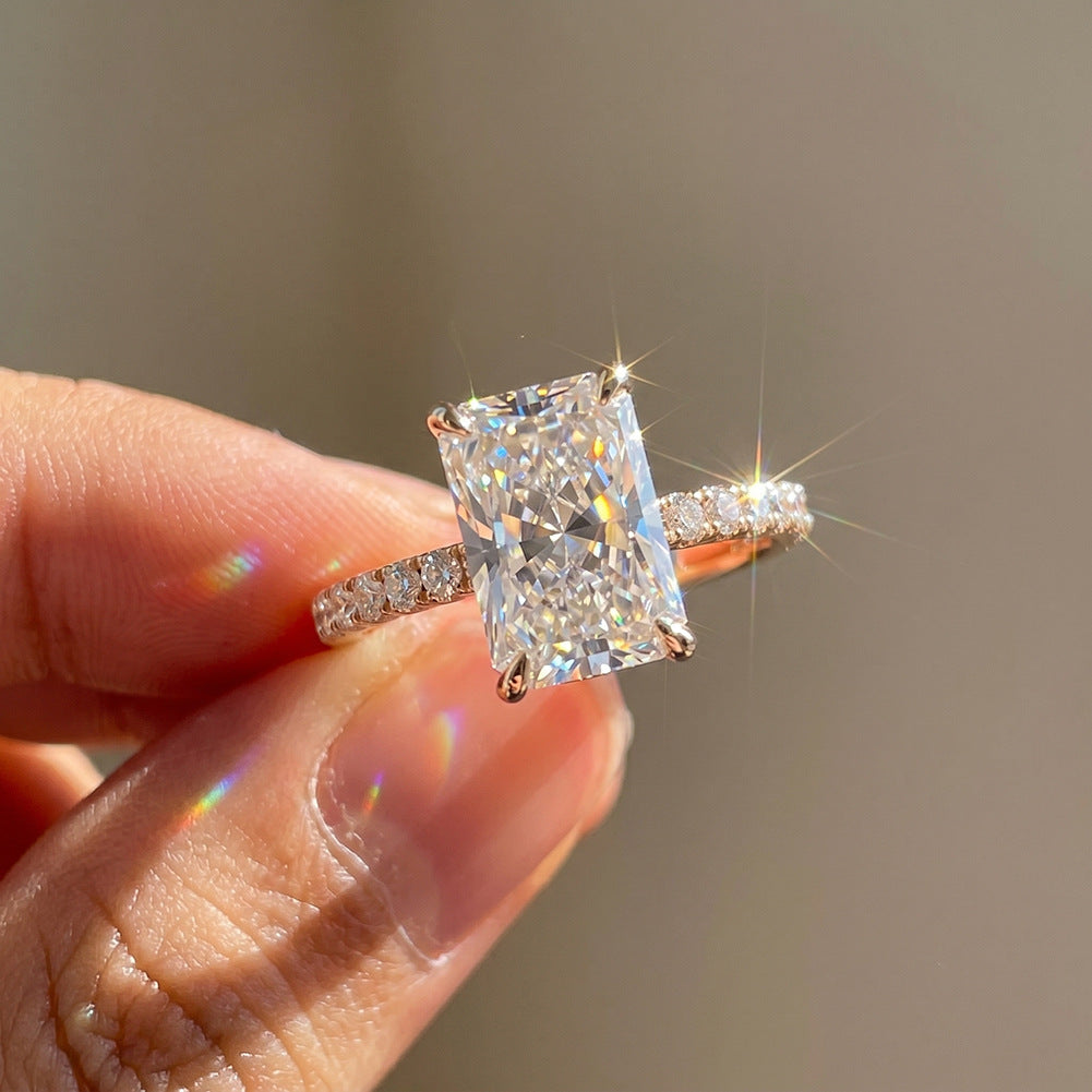 Close-up of hand holding 14k yellow gold 2ct radiant cut lab diamond pave engagement ring in sunlight showing sparkle