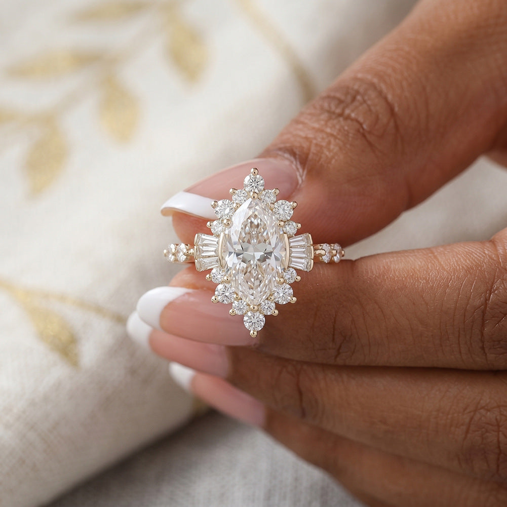 Close-up of hand holding 14k gold marquise cut lab diamond starburst halo ring showing baguette details