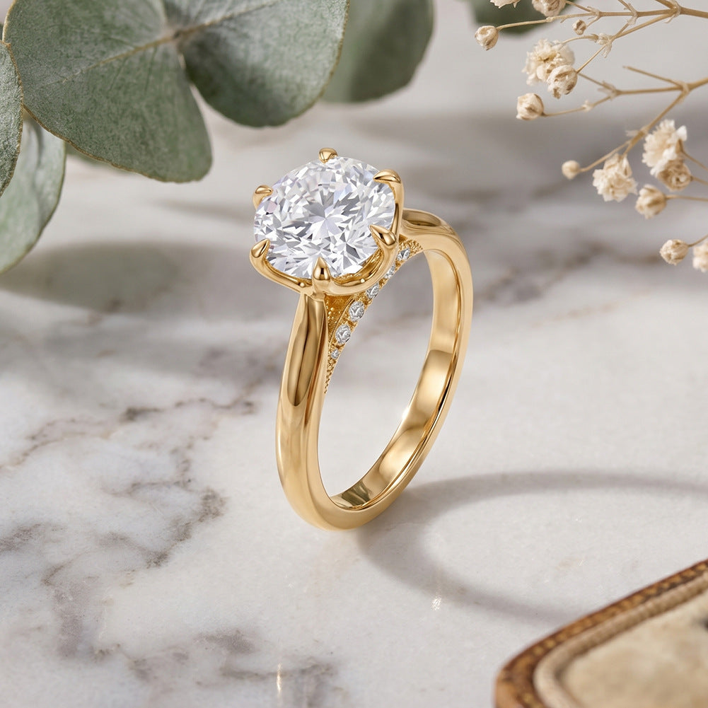 14k yellow gold round cut lab diamond six-prong solitaire engagement ring on white marble surface with dried flowers