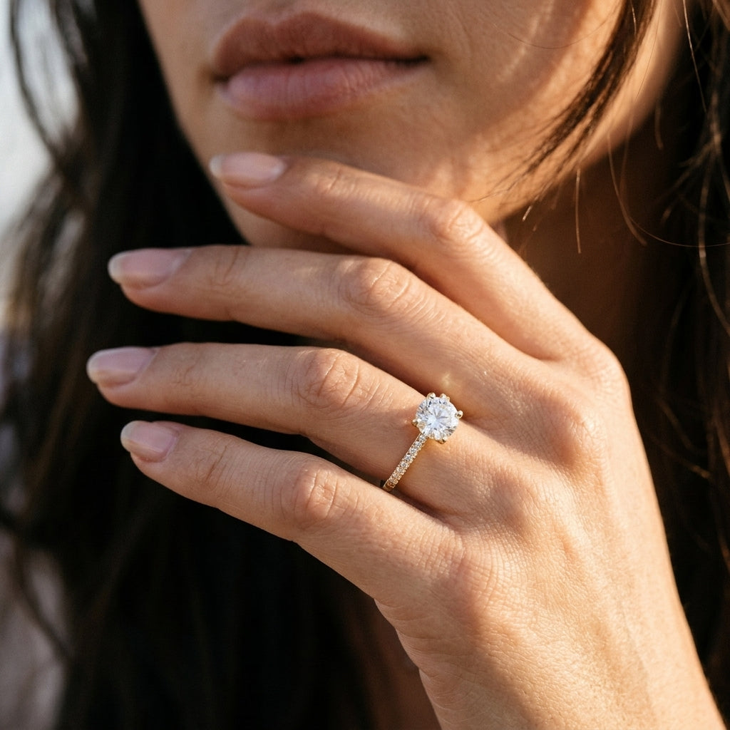 Model wearing 14k round lab-grown diamond solitaire engagement ring with pave accents on hand