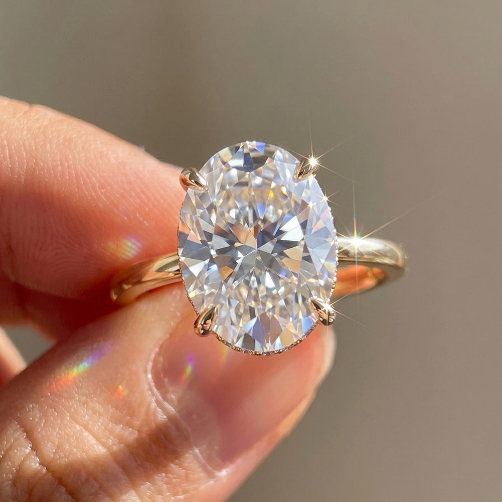 Hand holding 14k yellow gold 2 ct oval cut lab diamond solitaire engagement ring showing brilliant sparkle