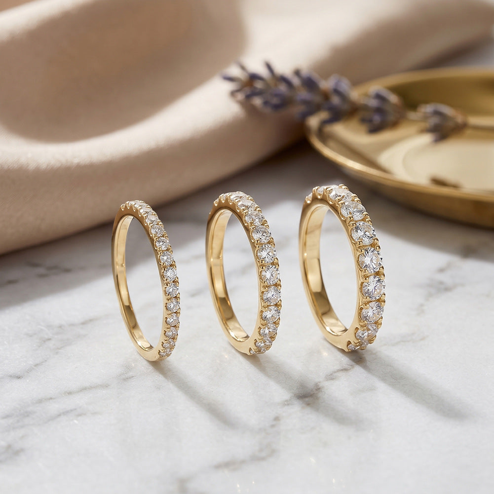 Three 14kt yellow gold round brilliant lab diamond half eternity band rings displayed on white marble