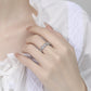 Hand wearing a silver ring with floral design on a white background