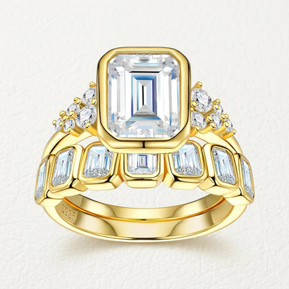 Studio display of 18k gold plated bezel set emerald cut moissanite bridal ring set with matching bezel eternity band.