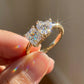 Close-up of hand holding 18k gold heart and princess cut toi et moi lab diamond ring in sunlight showing brilliance