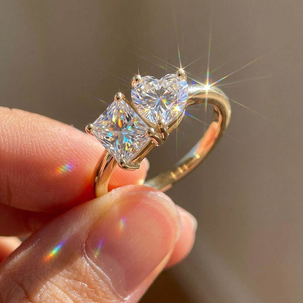 Close-up of hand holding 18k gold heart and princess cut toi et moi lab diamond ring in sunlight showing brilliance