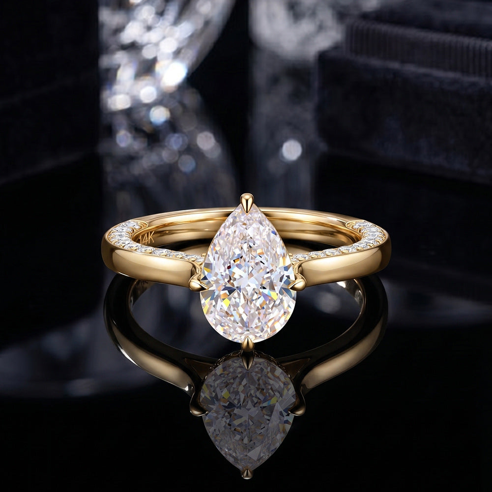 18k yellow gold pear cut lab diamond hidden halo engagement ring on black reflective surface with reflection