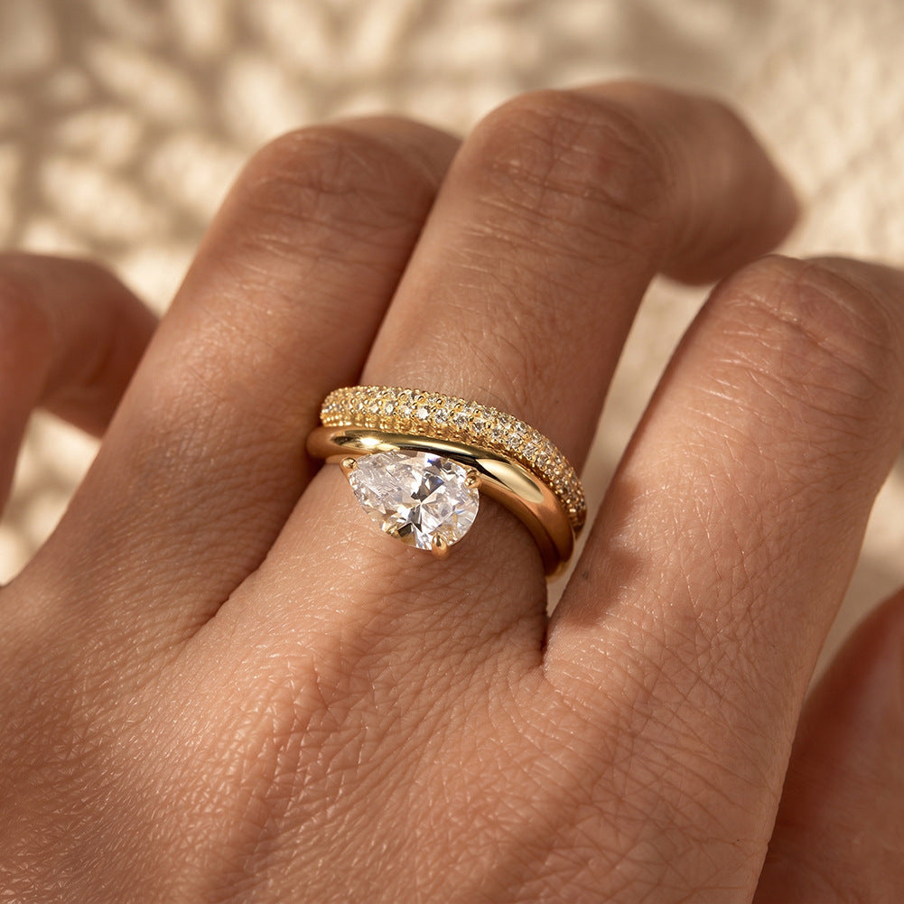 Model wearing 18k yellow gold pear cut lab diamond solitaire engagement stacking ring set on hand