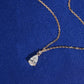 Angle view of 18k rose gold 1 carat pear cut lab-grown diamond clavicle pendant necklace on blue fabric