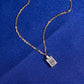 Angle view of 18k rose gold 1 carat radiant cut lab-grown diamond clavicle pendant necklace on blue fabric
