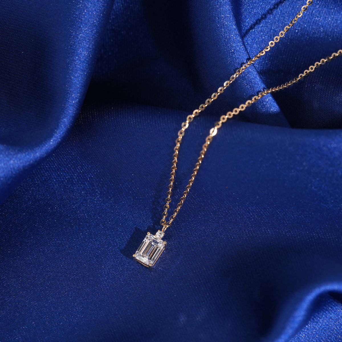Close up view of 1 carat radiant cut lab-grown diamond in 18k rose gold setting on blue silk