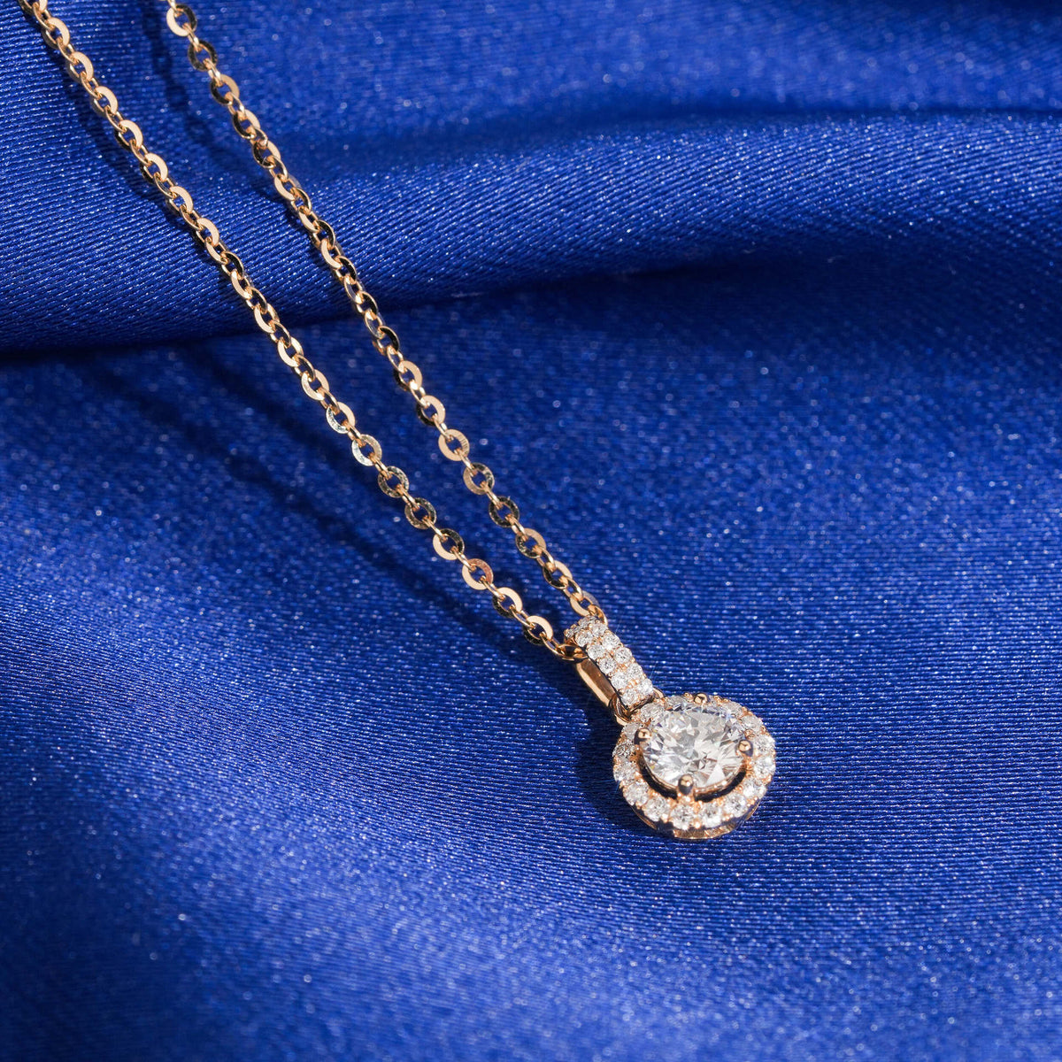 Close up view of 5mm round halo lab-grown diamond pendant with pave bail in 18k rose gold setting