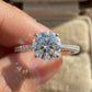 Close-up of fingers holding 18k white gold round lab-grown diamond solitaire ring with pave accents in soft sunlight