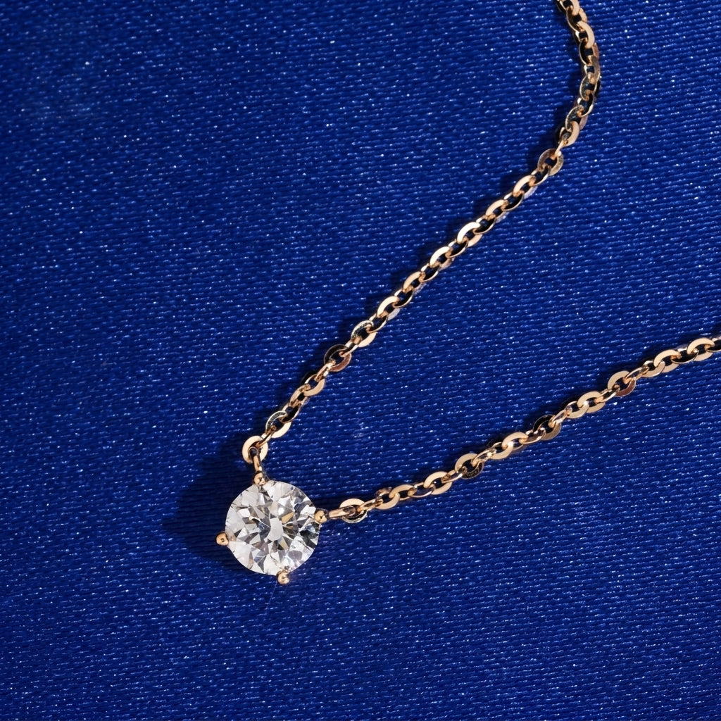Angle view of 18k yellow gold 5.5mm solitaire lab-grown diamond pendant necklace on blue fabric