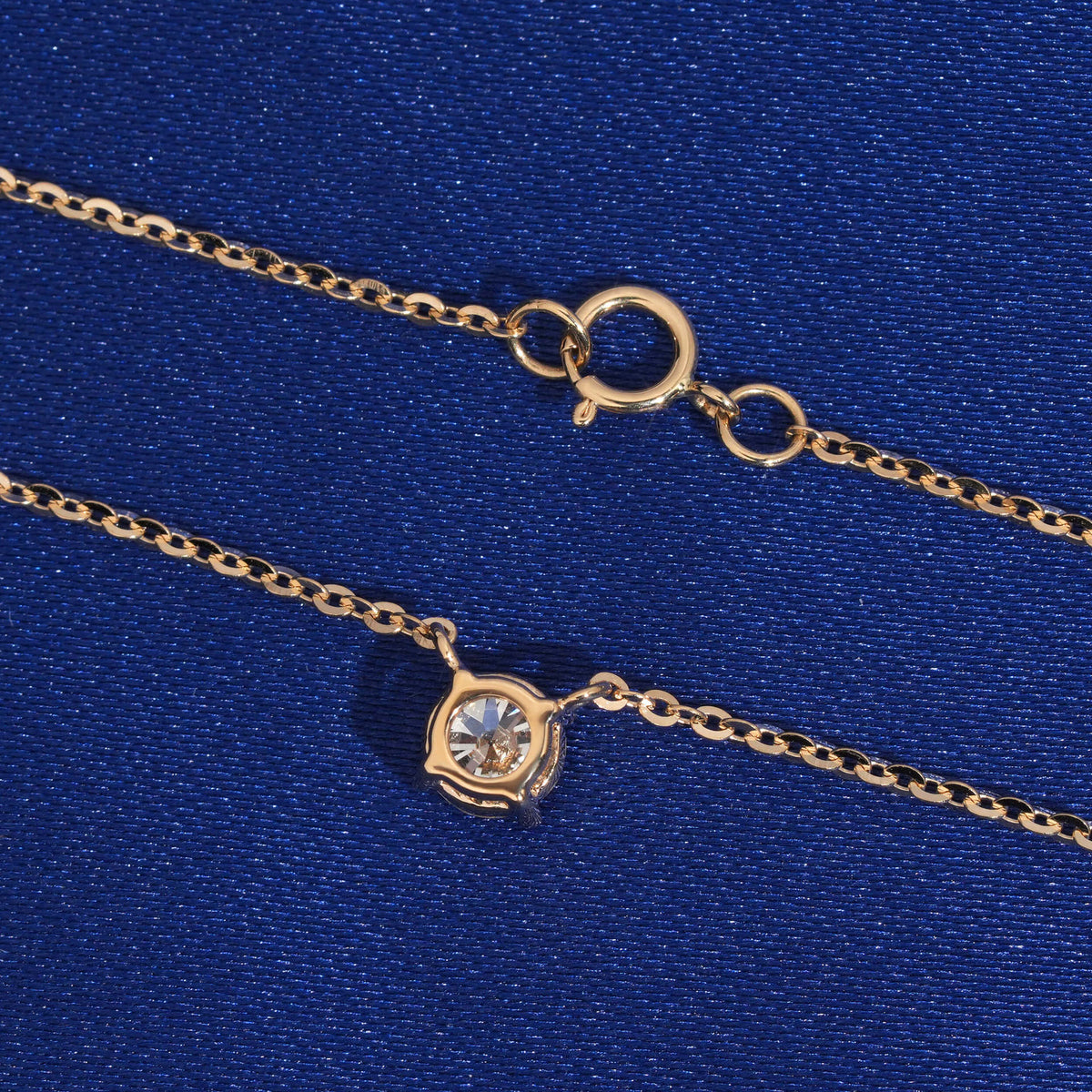 Back view of 4-prong setting and spring ring clasp of 18k yellow gold diamond pendant necklace