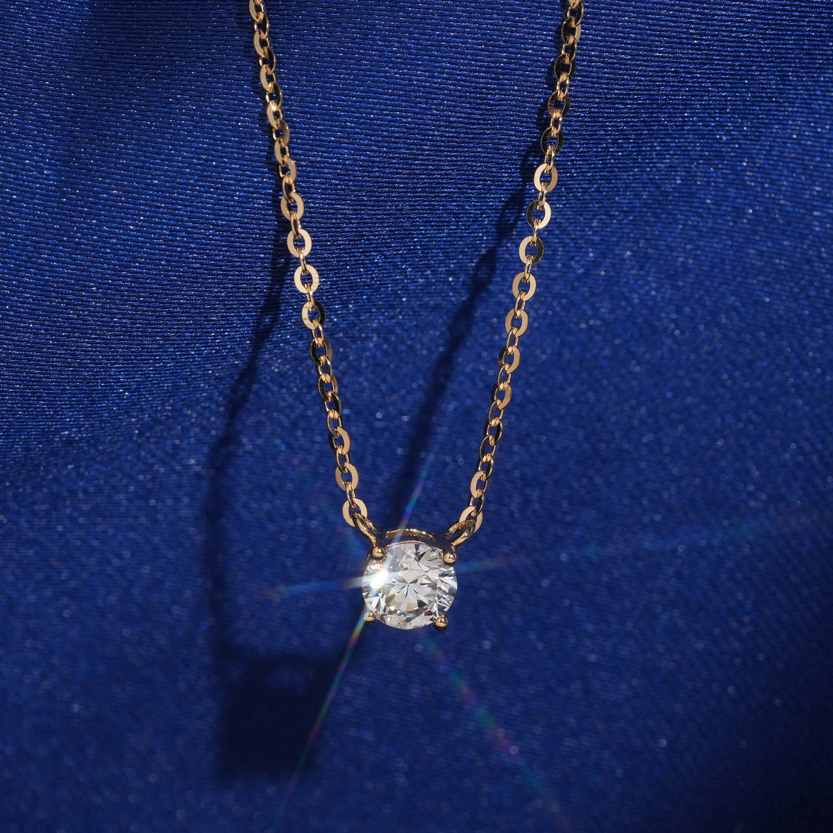 18k yellow gold 5.5mm solitaire lab-grown diamond pendant necklace sparkling on royal blue silk background   