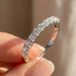 Hand holding 18kt white gold round brilliant lab diamond half eternity wedding ring in soft sunlight